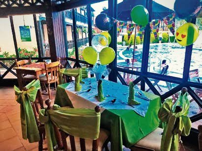Evento infantil al aire libre con globos de colores y sillas con lazos verdes.