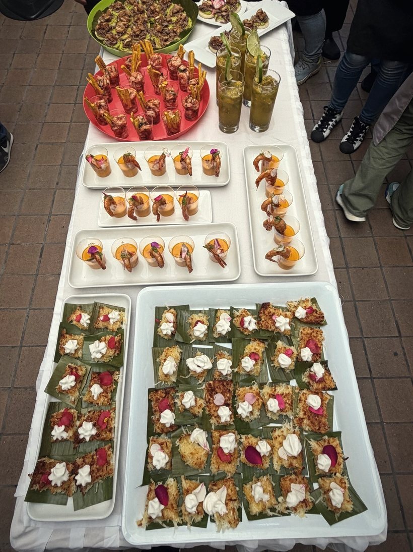 Mesa larga de pasabocas montada por Platino: ceviches, patacones y bocados sobre hoja de plátano.