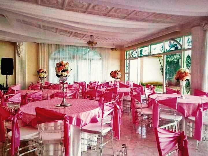 Salón de eventos con mesas redondas vestidas en fucsia y centros de flores.